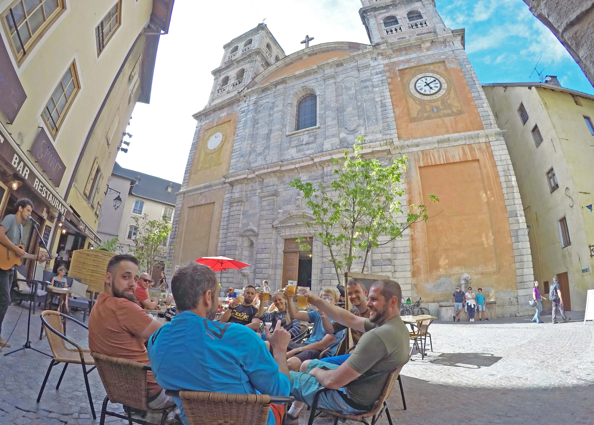 People at an outdoor café below a clock tower in Briançon’s old town