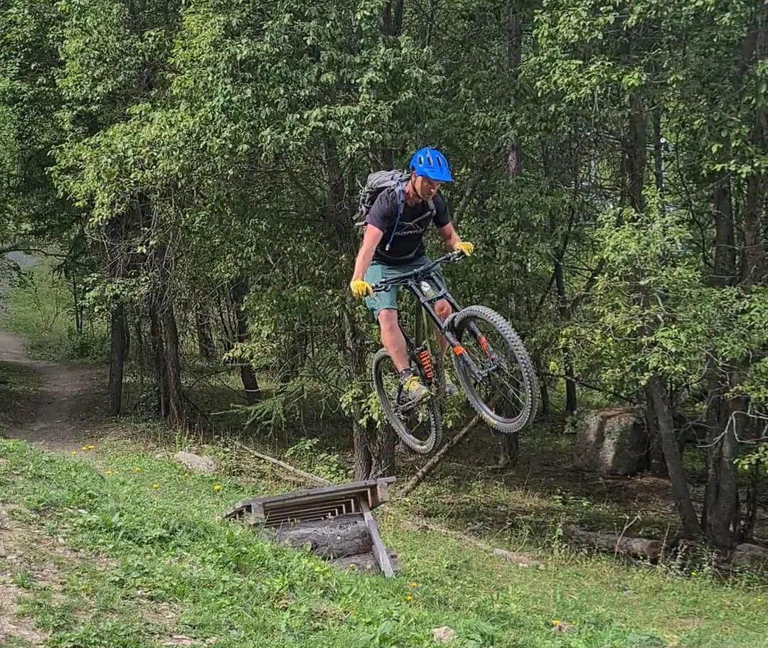 Mountain biker jumping over a trail feature in a green forest