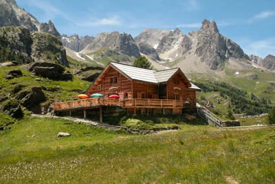 Wooden mountain refuge chalet in an Alpine meadow beneath rugged peaks