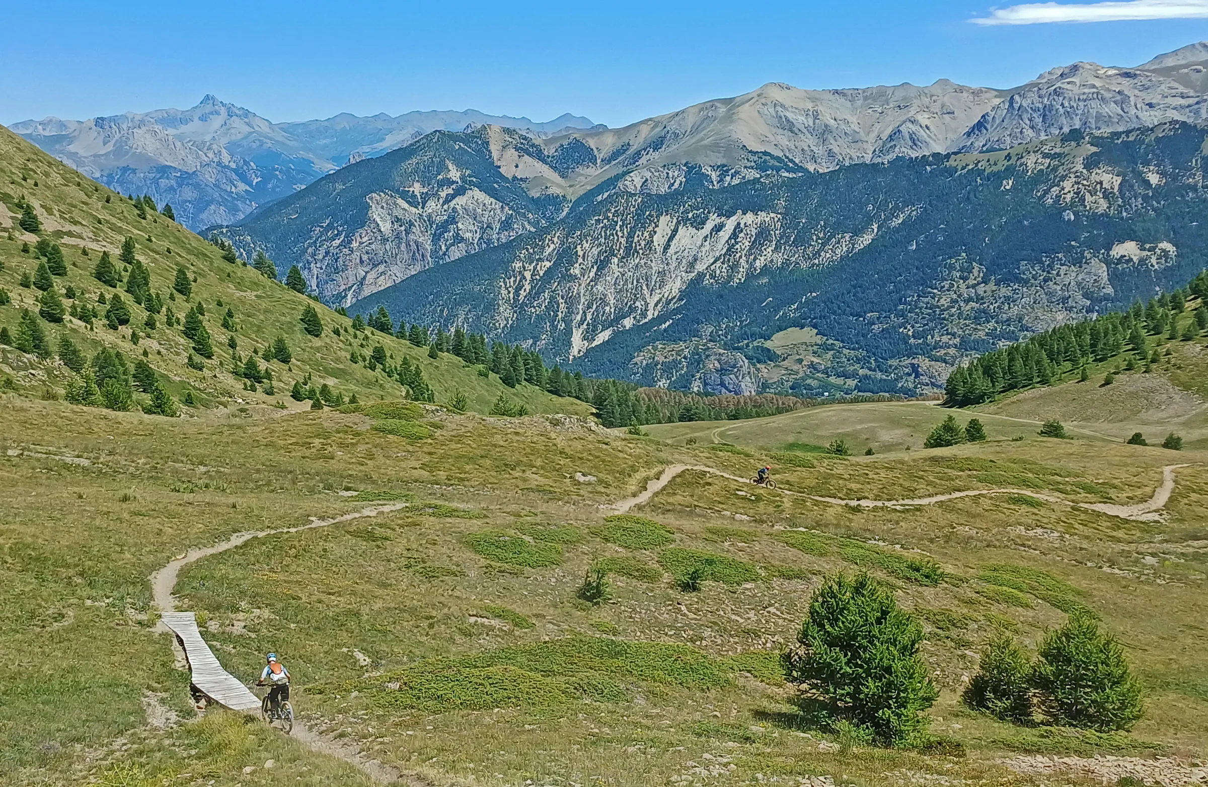 Rider following a flowing trail through an open high Alpine meadow