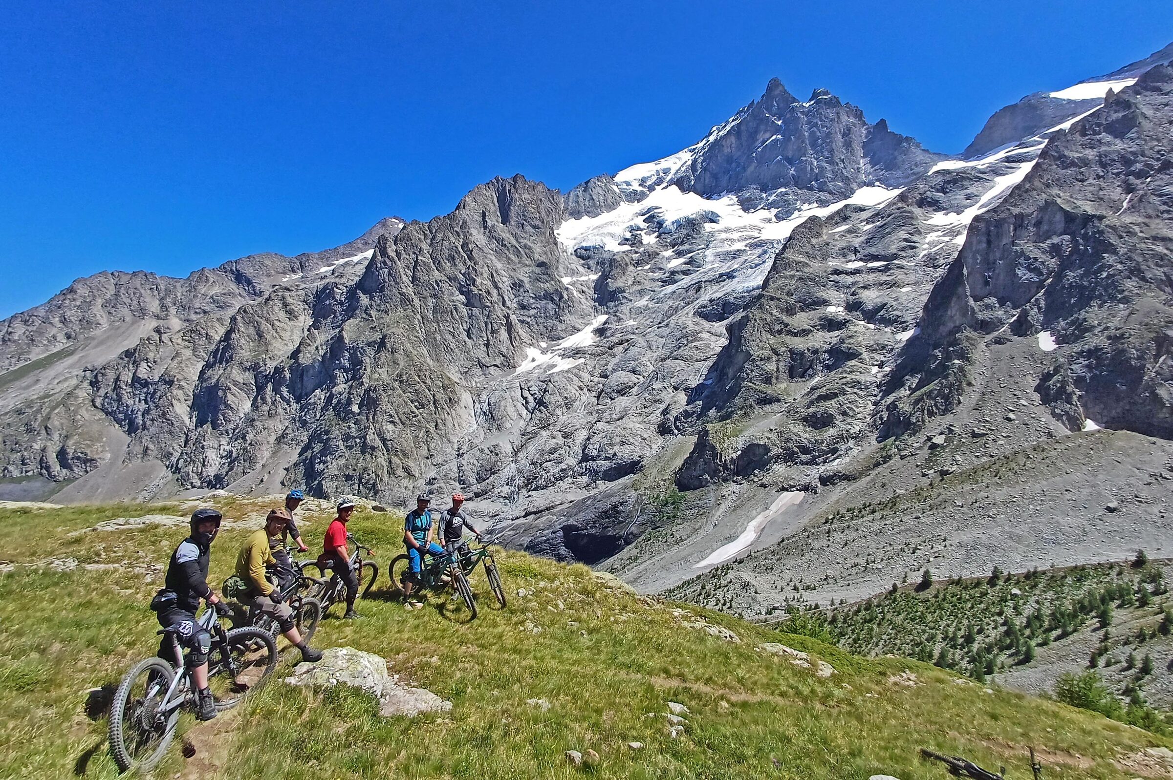 A group of mountain bikers beneath rocky Alpine peaks and glaciers